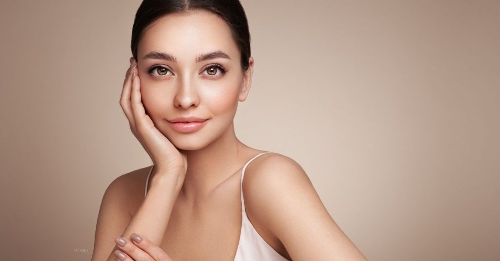 young female (model) with clear and smooth skin looks into the camera